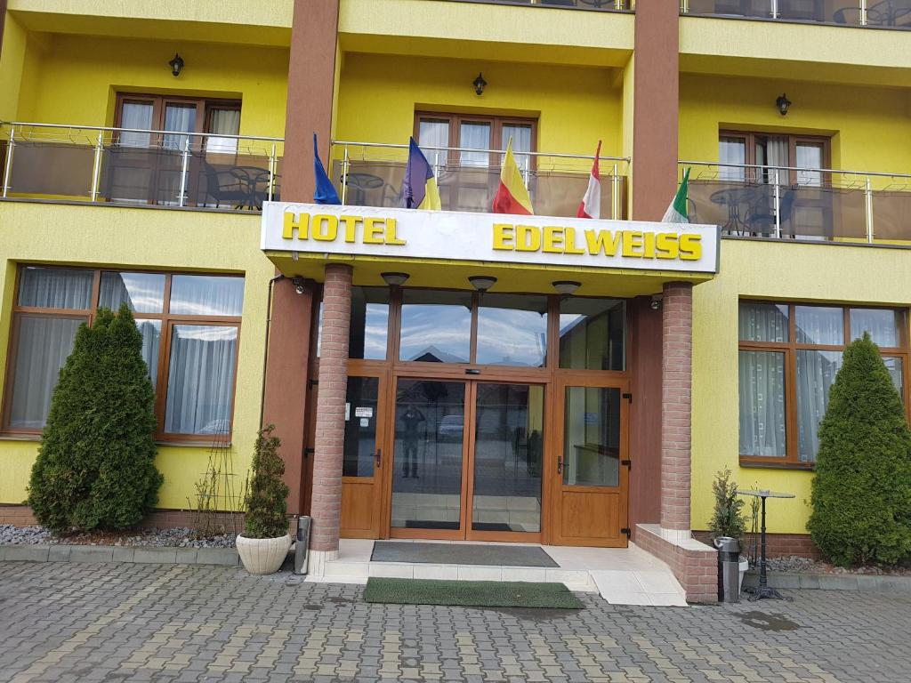 une entrée de l'hôtel avec des drapeaux devant elle dans l'établissement Hotel Edelweiss, à Mediaş