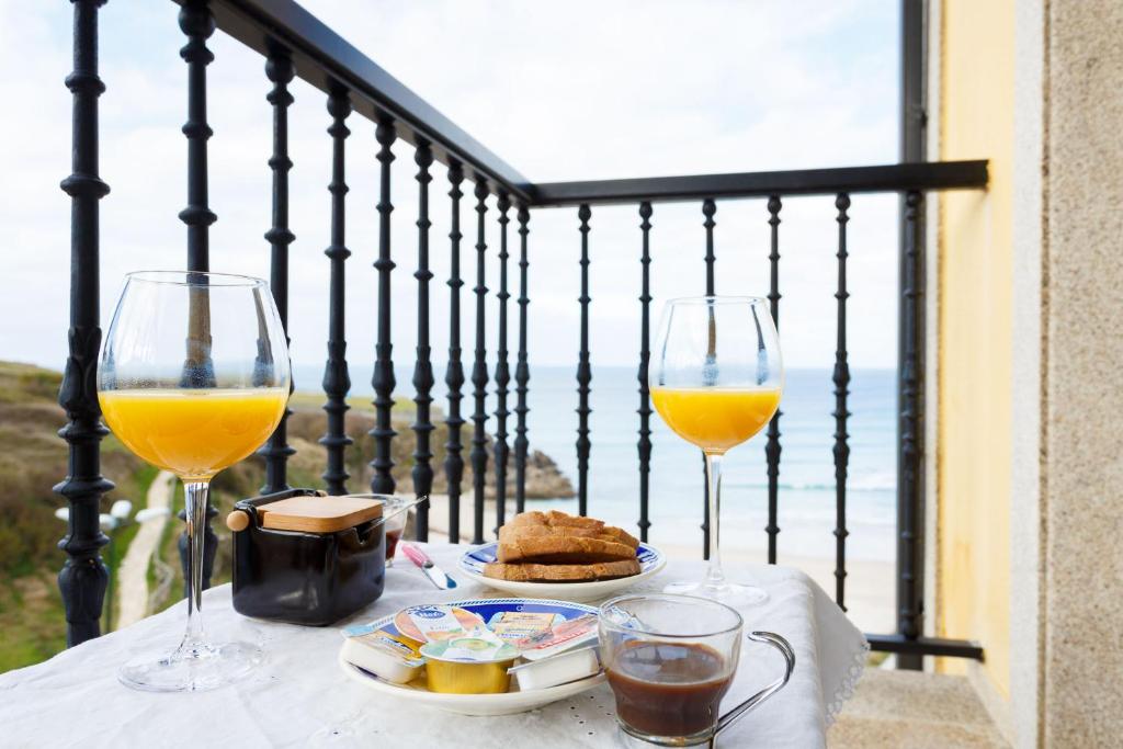 a table with two glasses of wine and food on a balcony at 1- Apartamento Playa Canido in Malpica