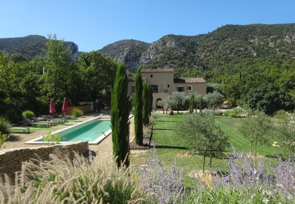 une villa avec une piscine et des montagnes en arrière-plan dans l'établissement L'arcadie Du Souleyan, à Oppède