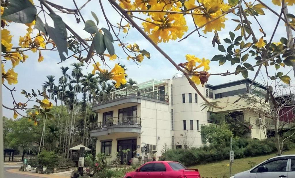 un bâtiment blanc avec une voiture rouge garée devant. dans l'établissement Sun Moon Talk, à Yuchi