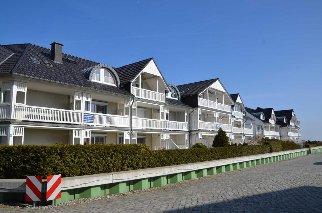 une rangée de maisons blanches aux toits noirs dans l'établissement Ferienwohnung Fischerhafen 14/Guent, à Karlshagen