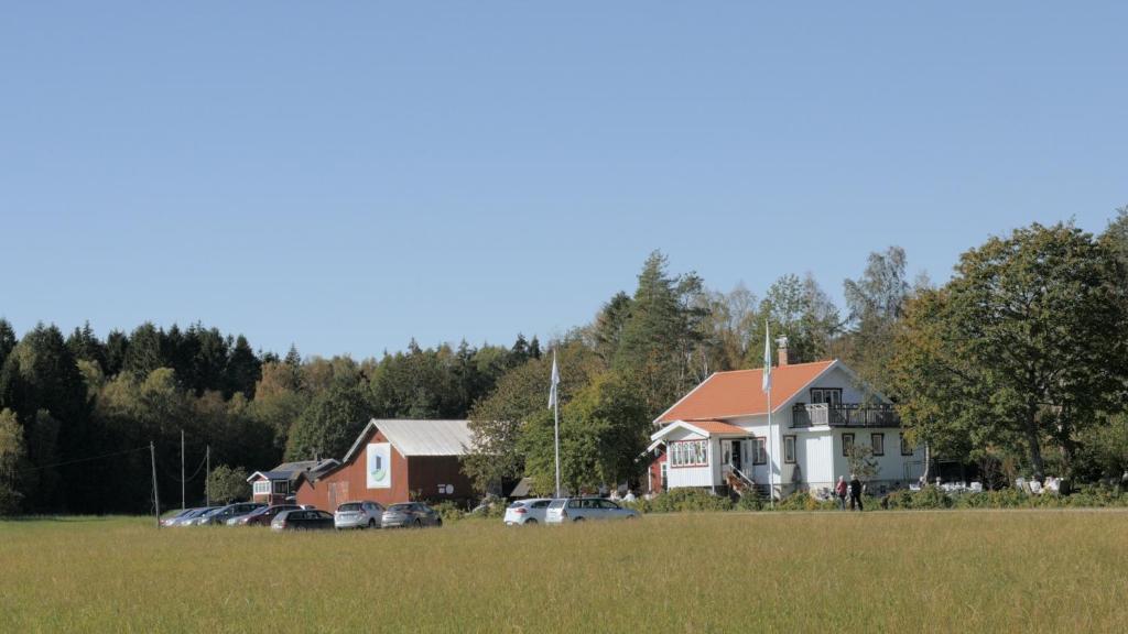 a house in a field with cars parked in a field at Tavlebords Honungsgård in Tegneby