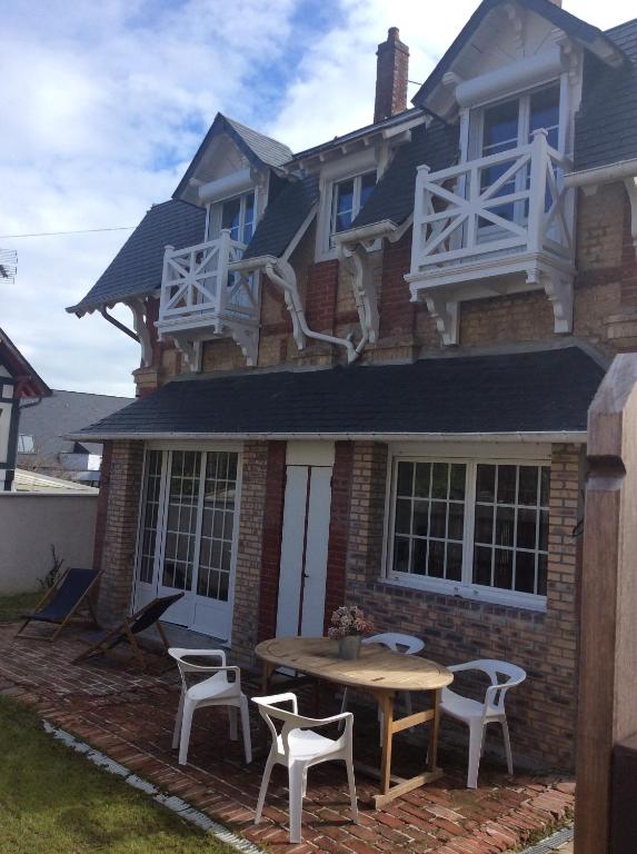 een huis met een tafel en stoelen ervoor bij L’annexe in Villers-sur-Mer