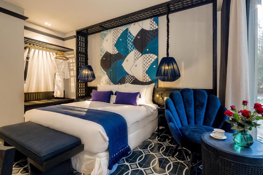 Habitación de hotel con cama y silla azul en Sol An Bang Beach Resort & Spa, en Hoi An