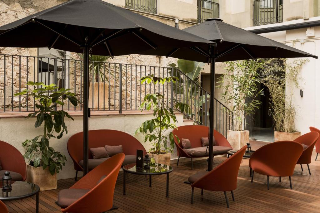 a patio with tables and chairs and an umbrella at Petit Palace Boqueria Garden in Barcelona