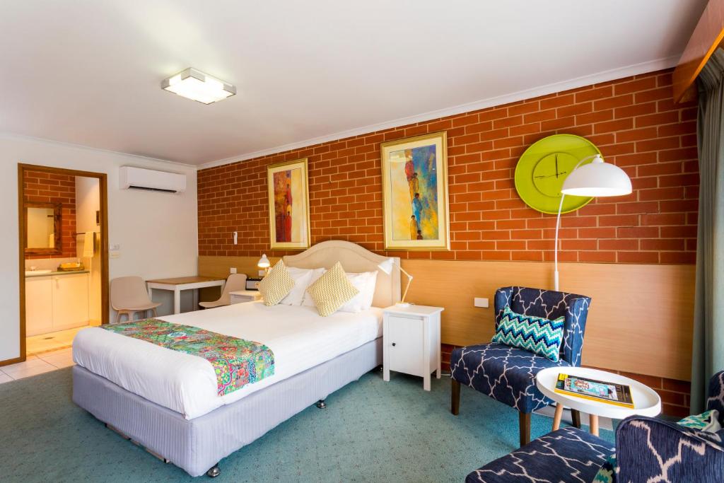 ein Hotelzimmer mit einem Bett und einem Stuhl in der Unterkunft Yackandandah Central in Yackandandah