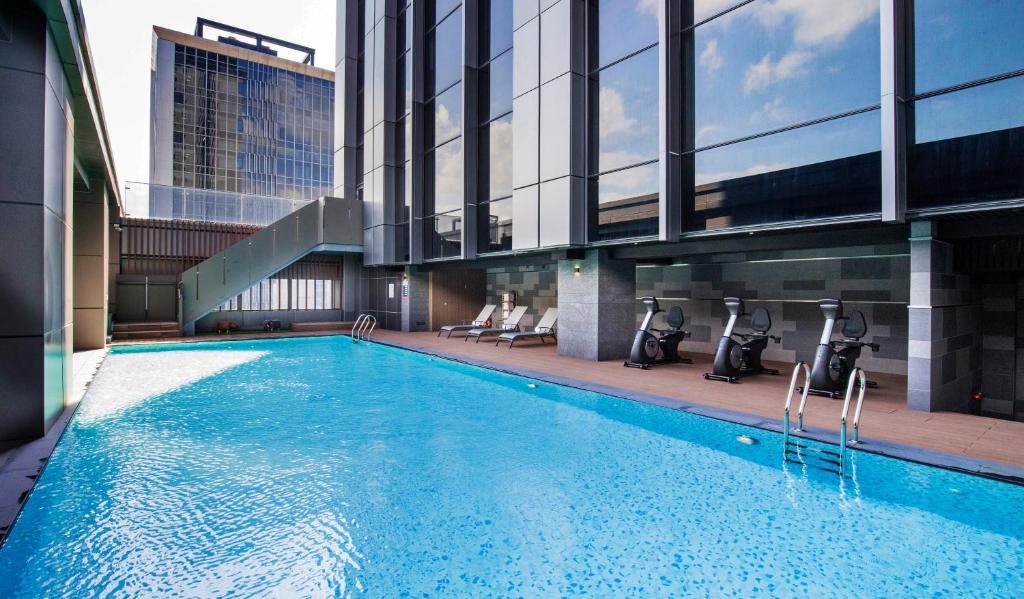 a swimming pool with chairs and a building at Caesar Metro Taipei in Taipei