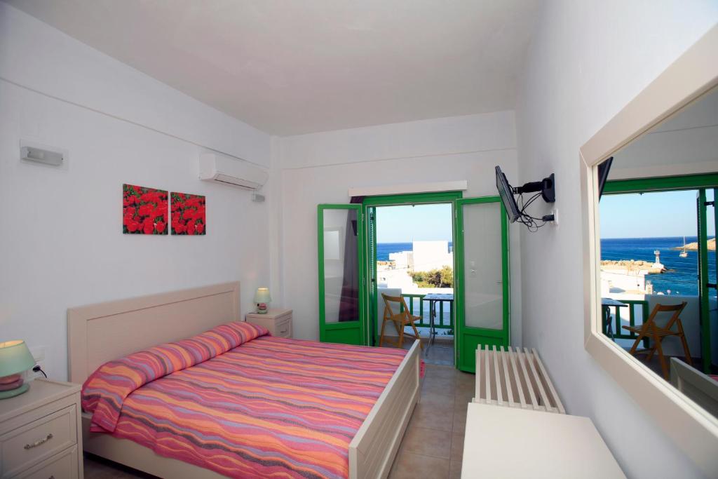 a bedroom with a bed and a balcony with the ocean at Kastellos Apartments Sikinos in Alopronia