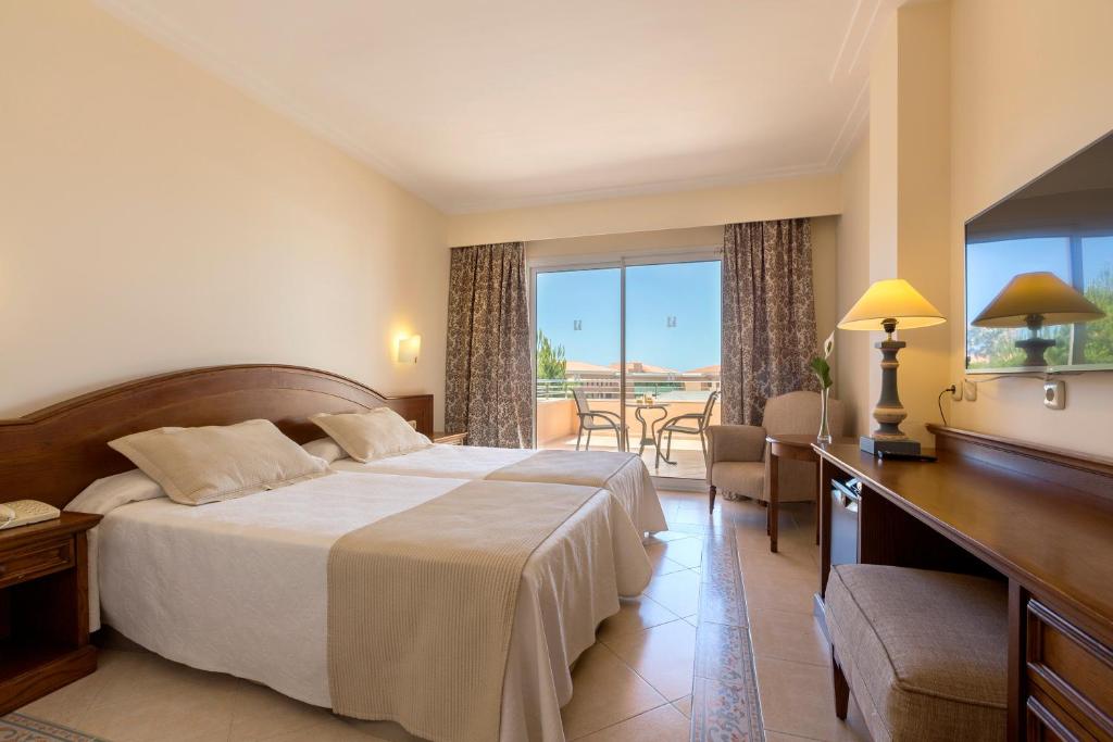 a hotel room with a bed and a table and chairs at Hipotels Barrosa Garden in Chiclana de la Frontera