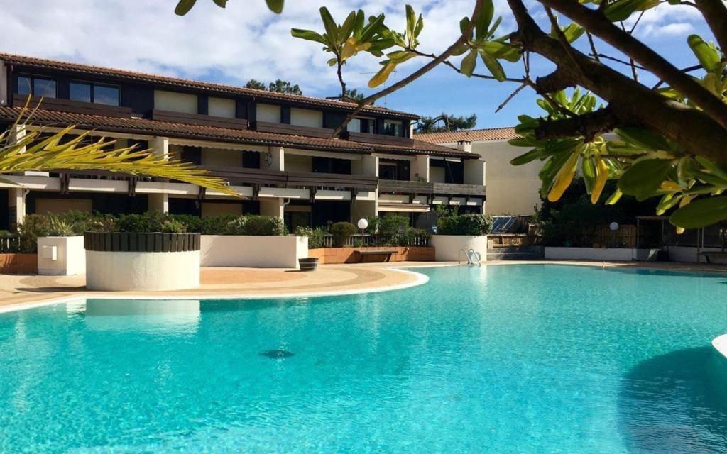 une grande piscine devant un immeuble dans l'établissement Ferret vacances, à Lège-Cap-Ferret