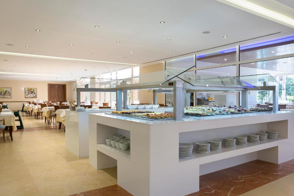 a restaurant with a counter with plates of food at Hipotels Barrosa Garden in Chiclana de la Frontera