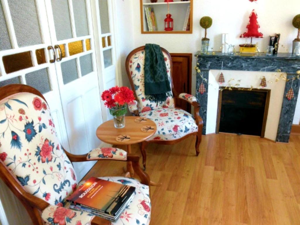 sala de estar con 2 sillas, mesa y chimenea en Maison Chêne Liège, en Maureillas