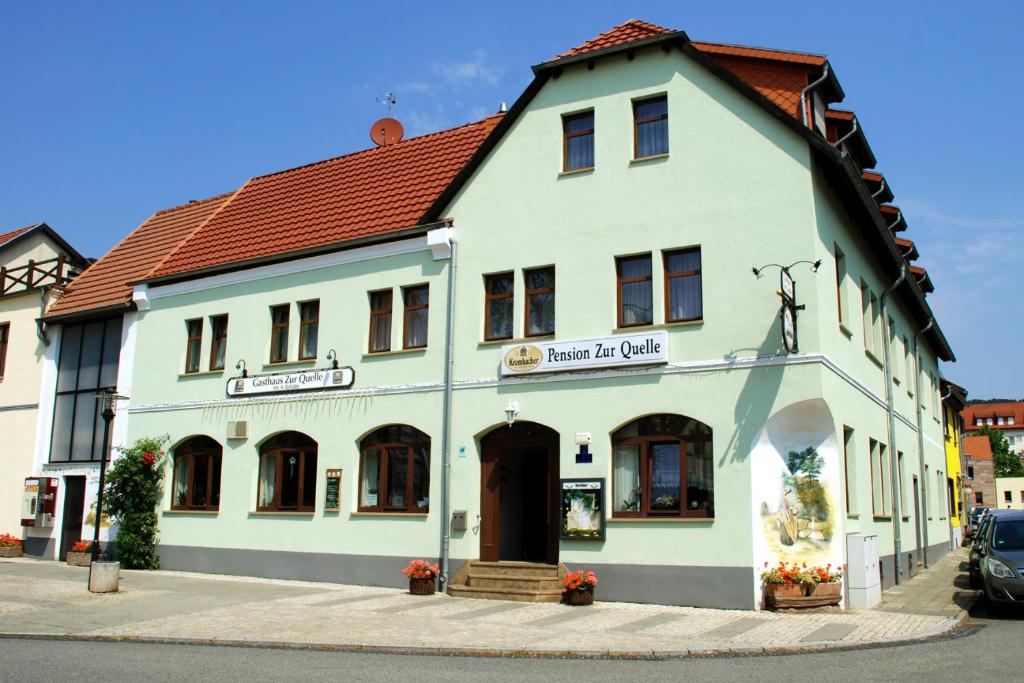 un edificio blanco con techo rojo en una calle en Pension Zur Quelle, en Bad Frankenhausen