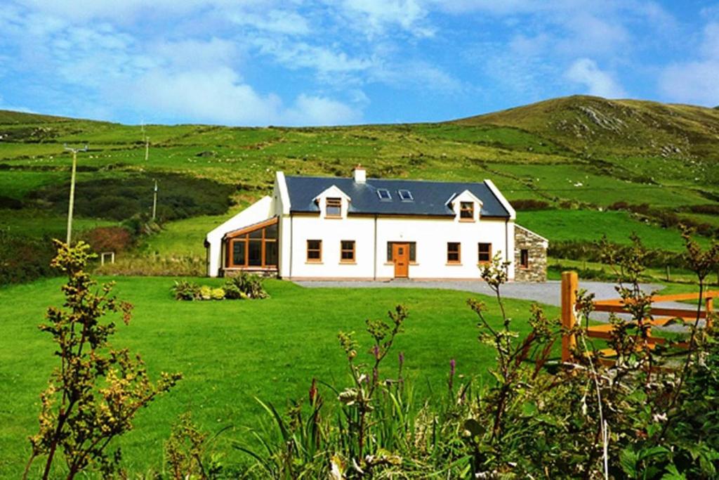 a white house on a hill with a green field at Chapel Cross House in Ballinskelligs