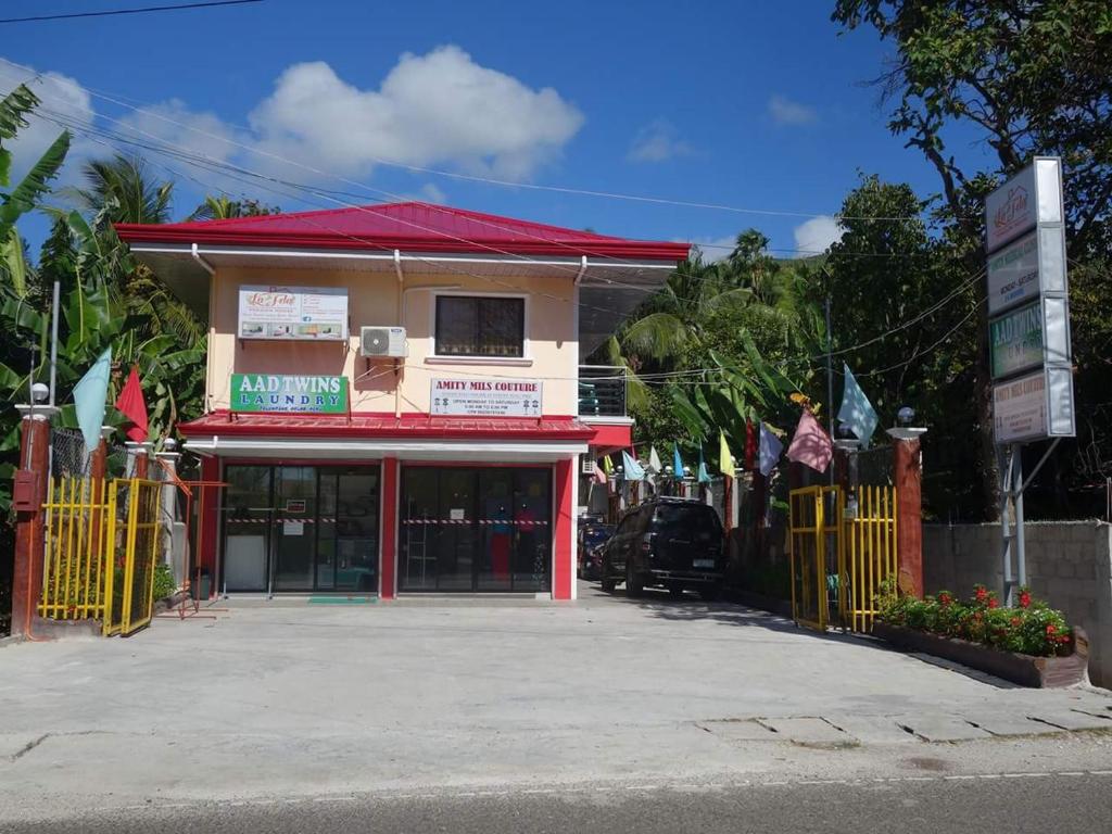 um edifício com um telhado vermelho e um portão em La Fela Pension House em Oslob