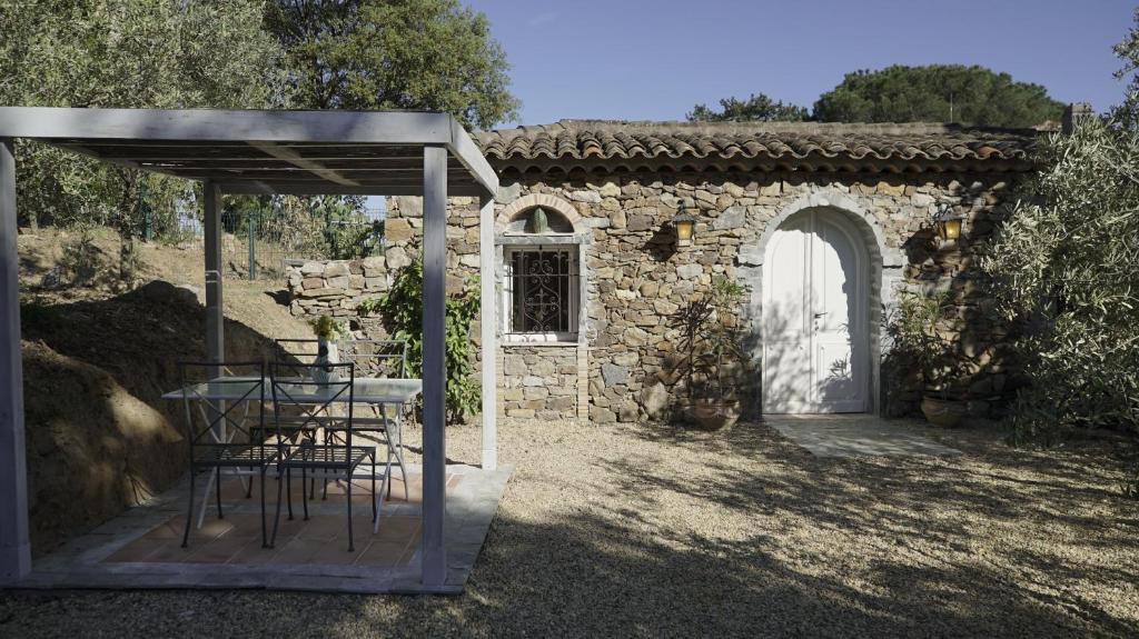 um pátio com uma mesa e cadeiras num edifício de pedra em La Maison des Oliviers em Cogolin