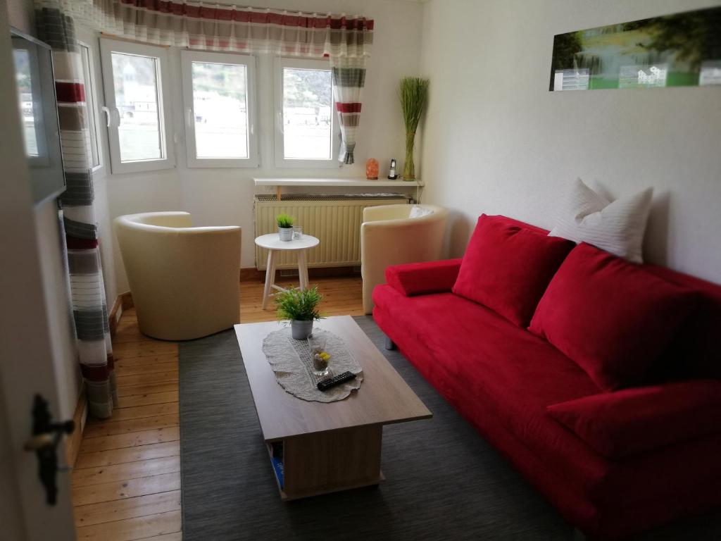 ein Wohnzimmer mit einem roten Sofa und einem Tisch in der Unterkunft Panorama-Rheinblick St. Goar in Sankt Goar