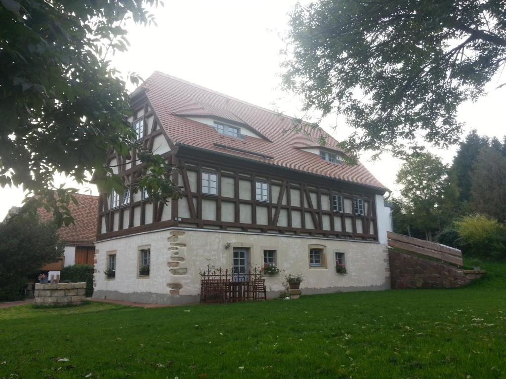 an old house with a red roof on a green field at Ferienwohnung "Alte Bauernstube" in Meißen