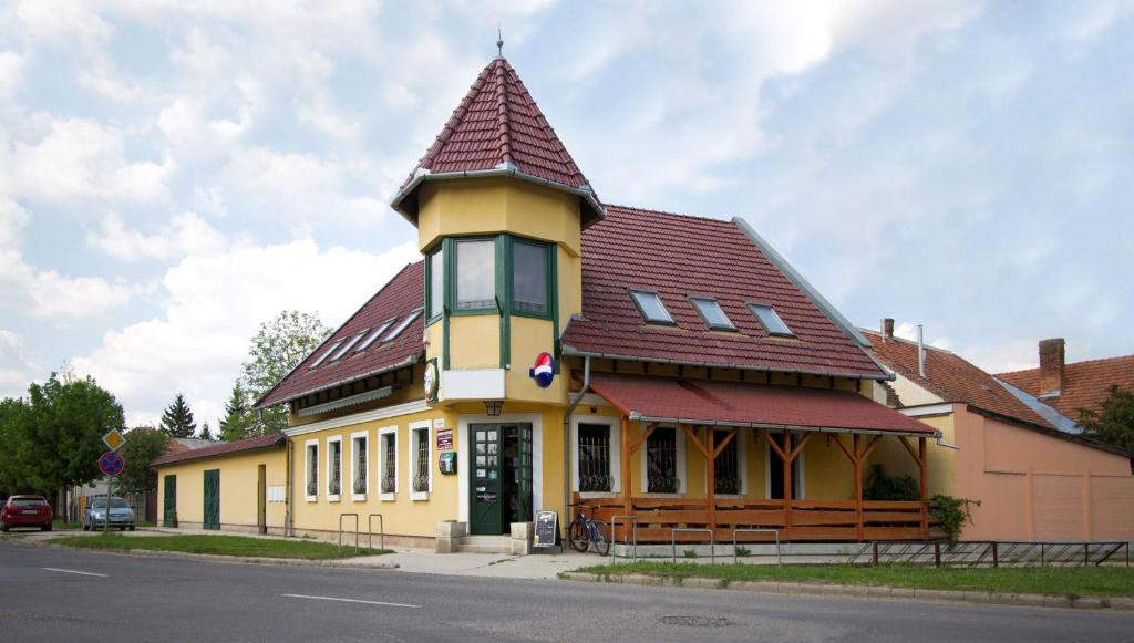 un gran edificio amarillo con techo rojo en Alíz Vendégház en Békéscsaba