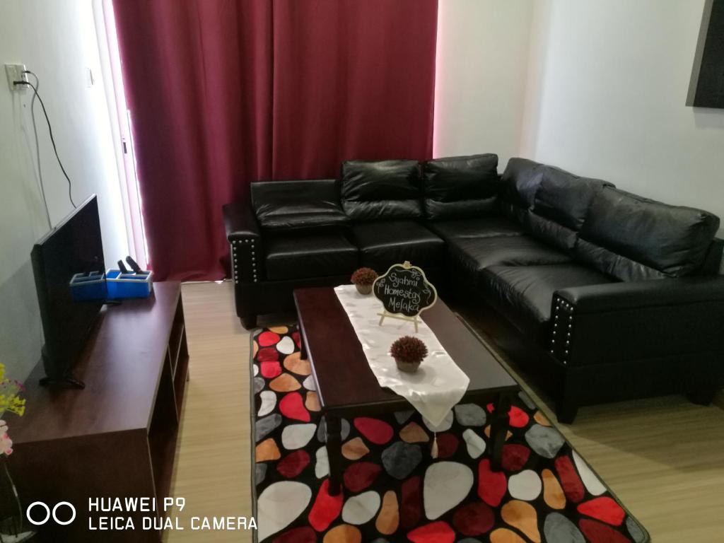 a living room with a black couch and a table at Syahmi Homestay Melaka in Melaka