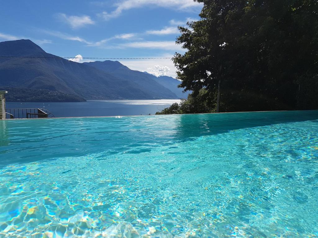 una gran piscina de agua azul con montañas al fondo en Residence Giglio Comer See, en Gravedona