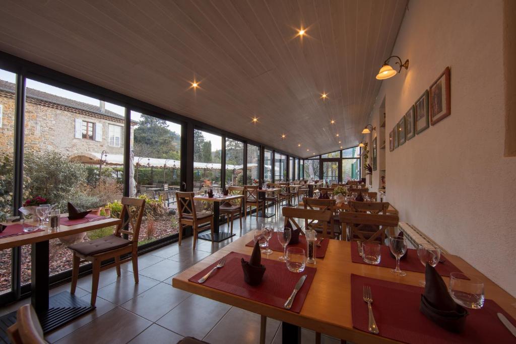 a restaurant with tables and chairs and large windows at Hotel Carmel in Les Vans