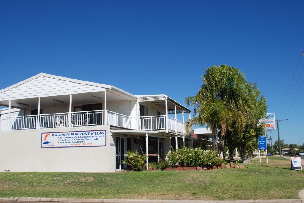 a white building with a palm tree in front of it at Kalbarri Seafront Villas in Kalbarri