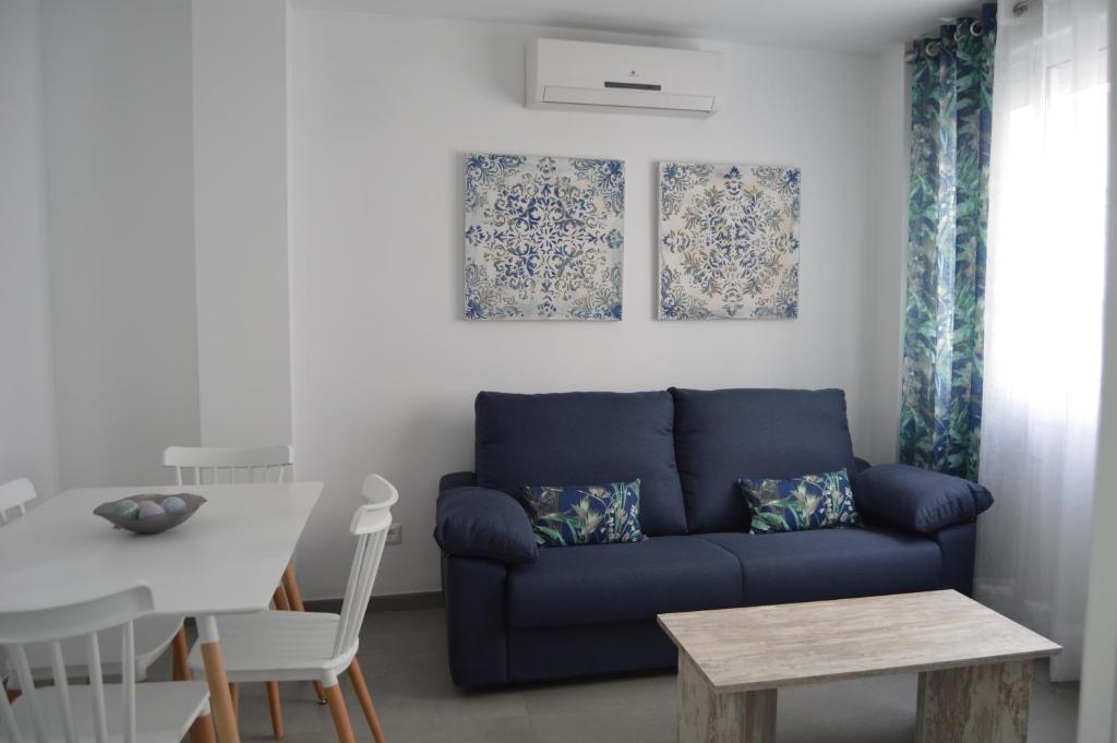 uma sala de estar com um sofá azul e uma mesa em APARTAMENTO AVENIDA 2 em Nerja