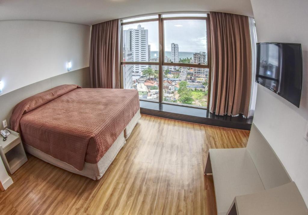 Marante Executive Hotel في ريسيفي: غرفة فندقية بسرير ونافذة كبيرة