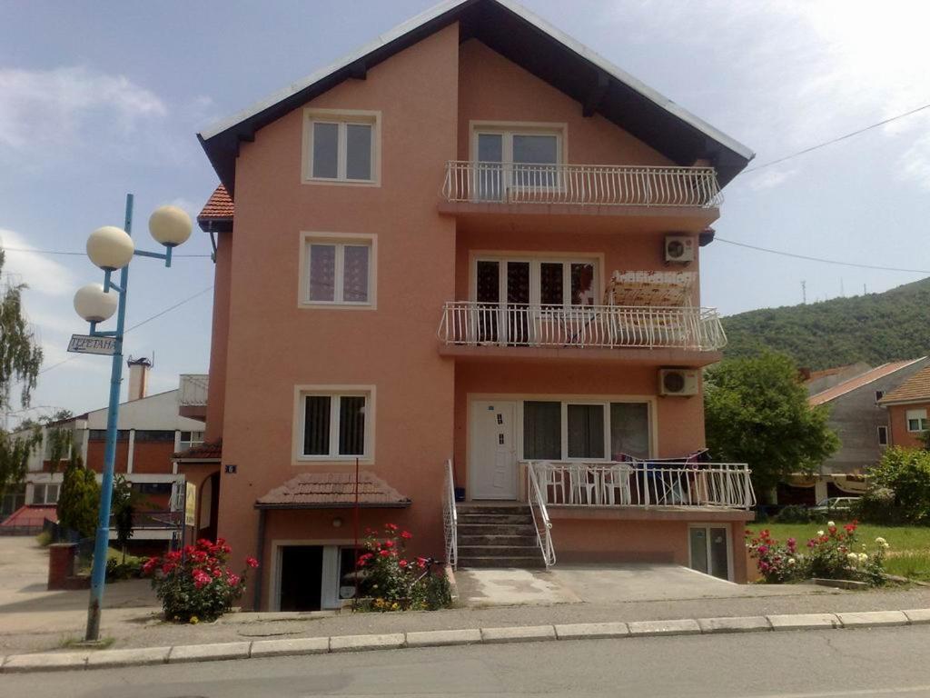 ein großes orangefarbenes Haus mit einer Treppe und einem Balkon in der Unterkunft Apartments Petkovic in Sokobanja