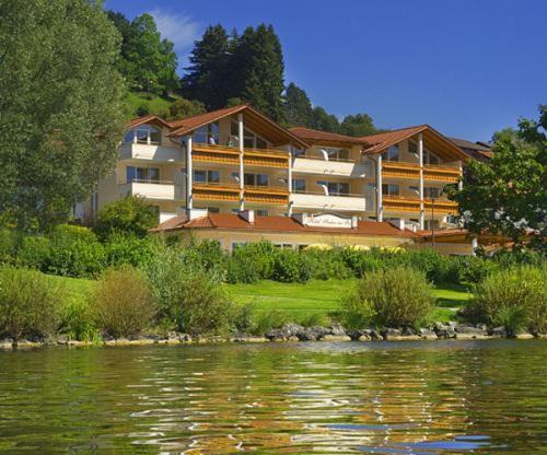 ein großes Gebäude neben einem Wasserkörper in der Unterkunft Hotel Fischer am See in Füssen