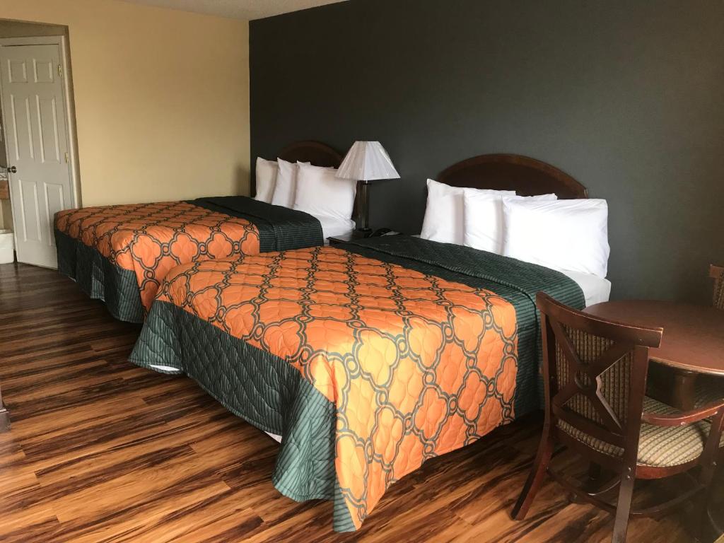 a hotel room with two beds and a table at Knights Inn Lumberton in Lumberton