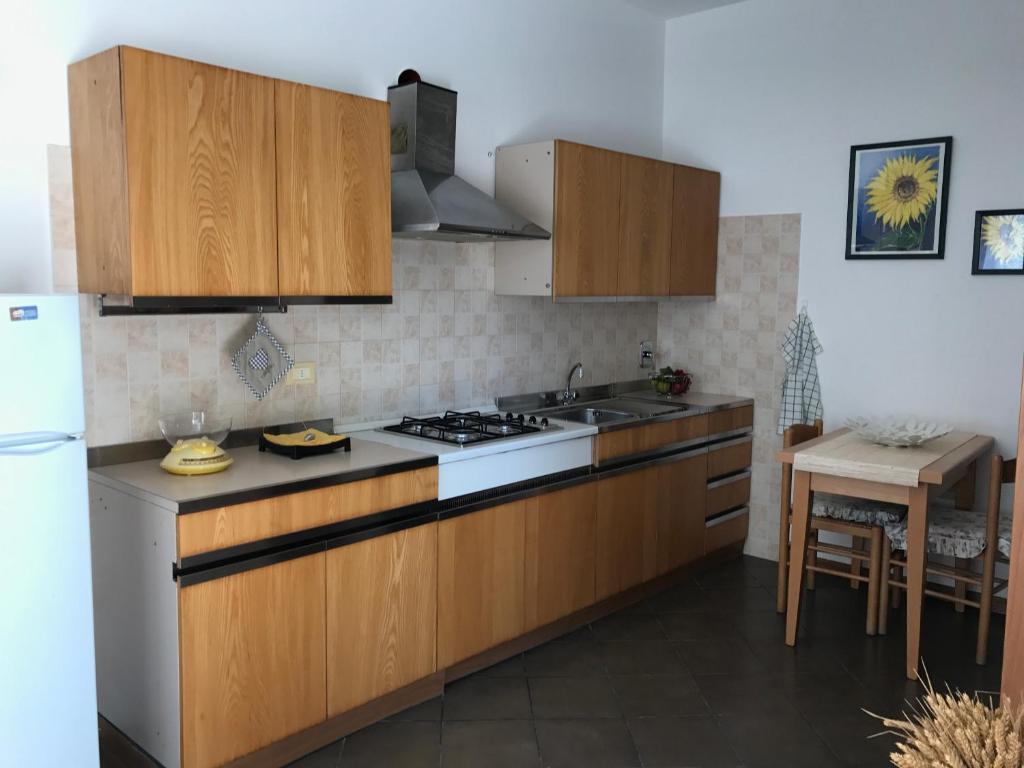La cuisine est équipée de placards en bois et d'un four avec plaques de cuisson. dans l'établissement Affittacamere Fiumicello, à Papariano