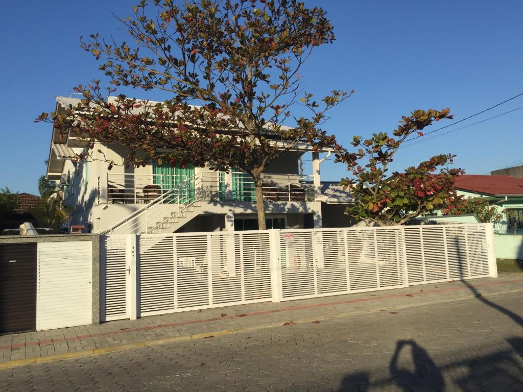 una cerca blanca frente a una casa con un árbol en Residencial Leone, en Bombinhas