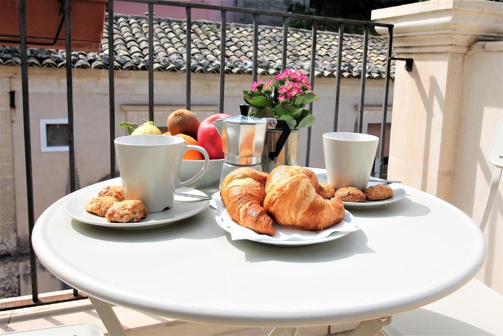 un tavolo con piatti di croissant e tazze di caffè di Le Luci su Ibla - Ospitalità con vista a Ragusa