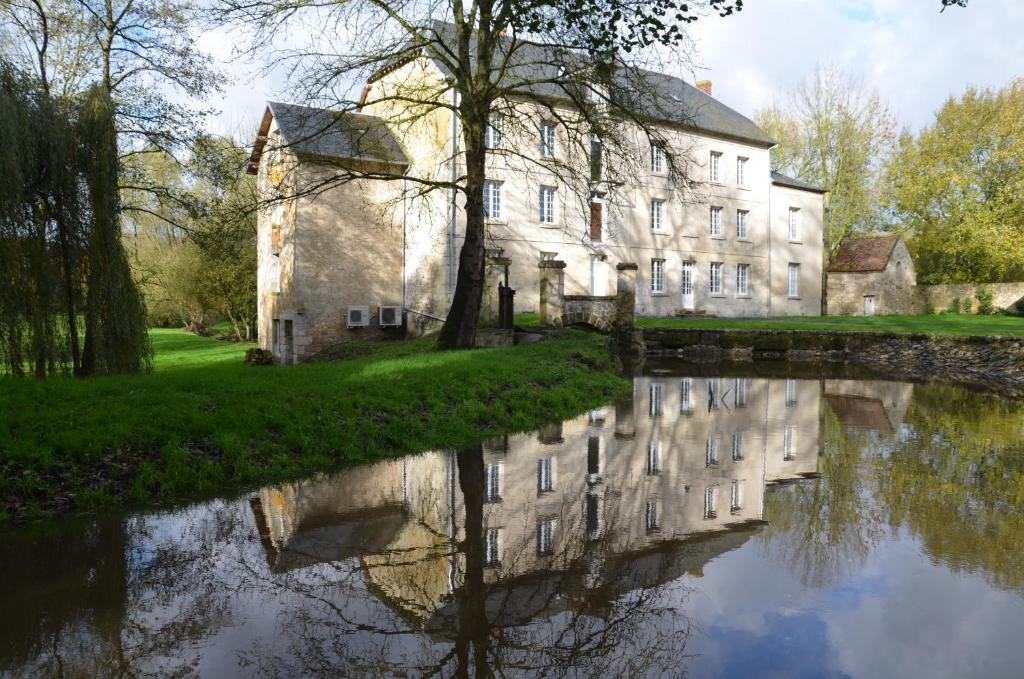 un edificio antiguo con un reflejo en un río en Moulin Saurele, en Mont-Notre-Dame