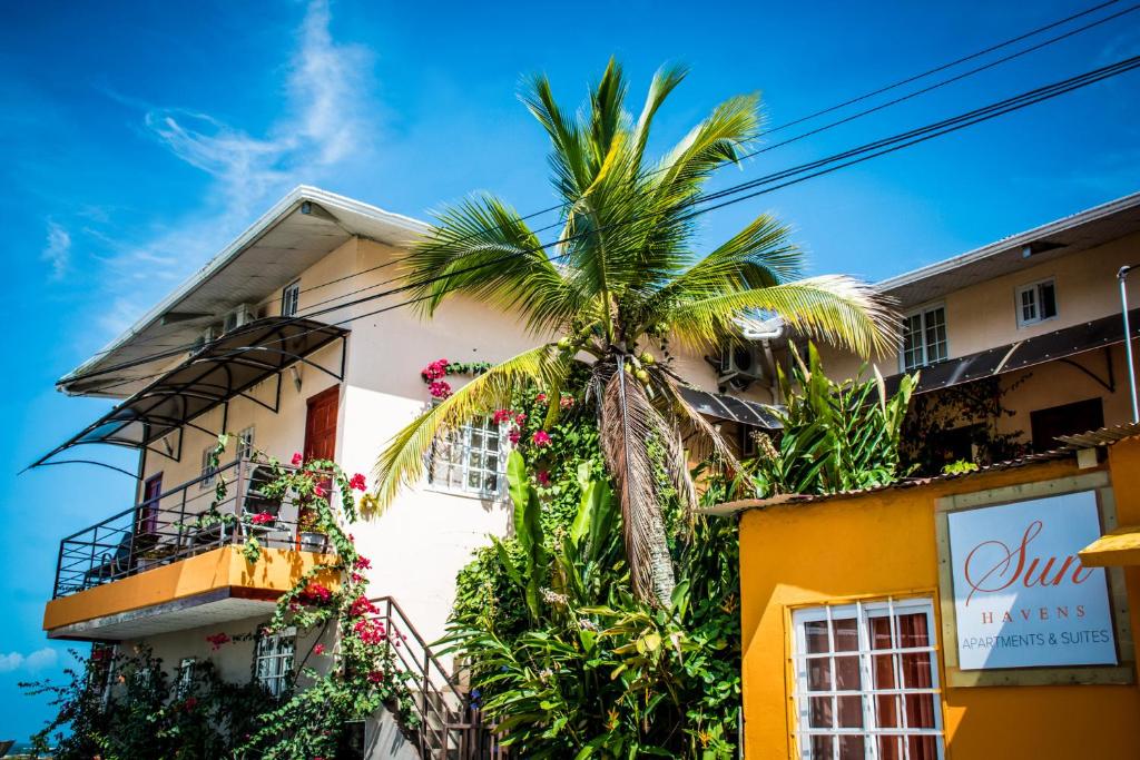 un bâtiment avec un palmier en face dans l'établissement Sun Havens Apartments & Suites, à Bocas del Toro