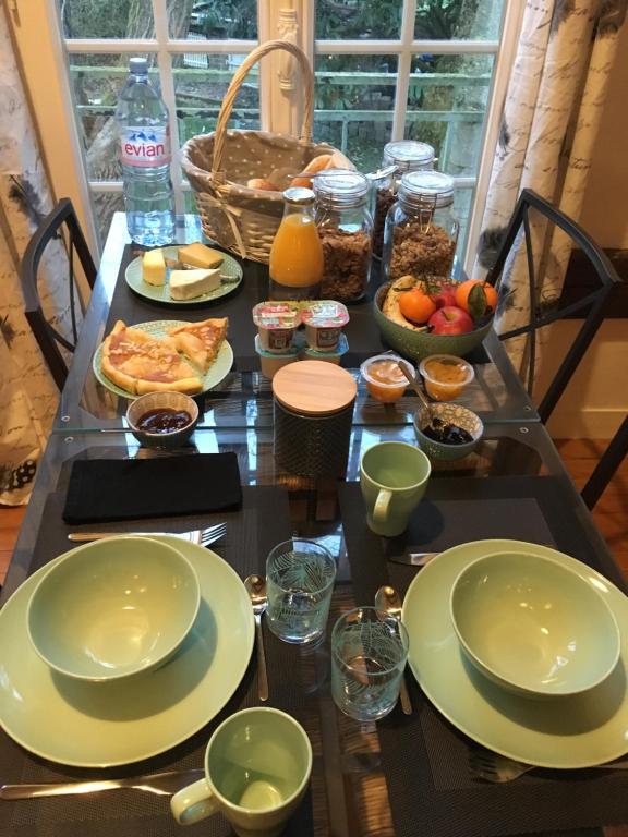 a table with plates and bowls of food on it at B&amp;B Au bois dormant chambres d hotes in Tillé