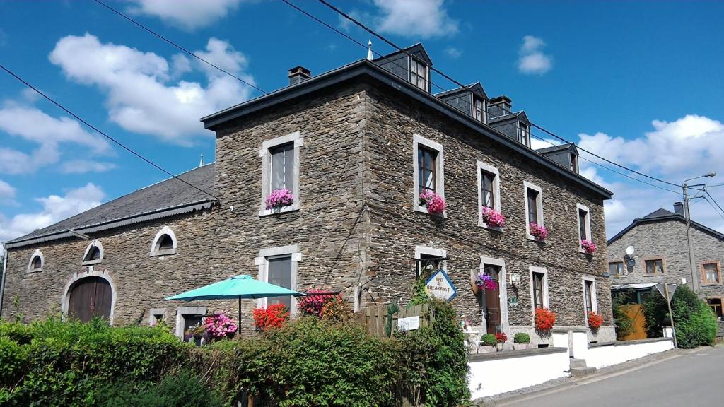 a brick building with flowers on the windows at Gîte Le Courtil in Bouillon