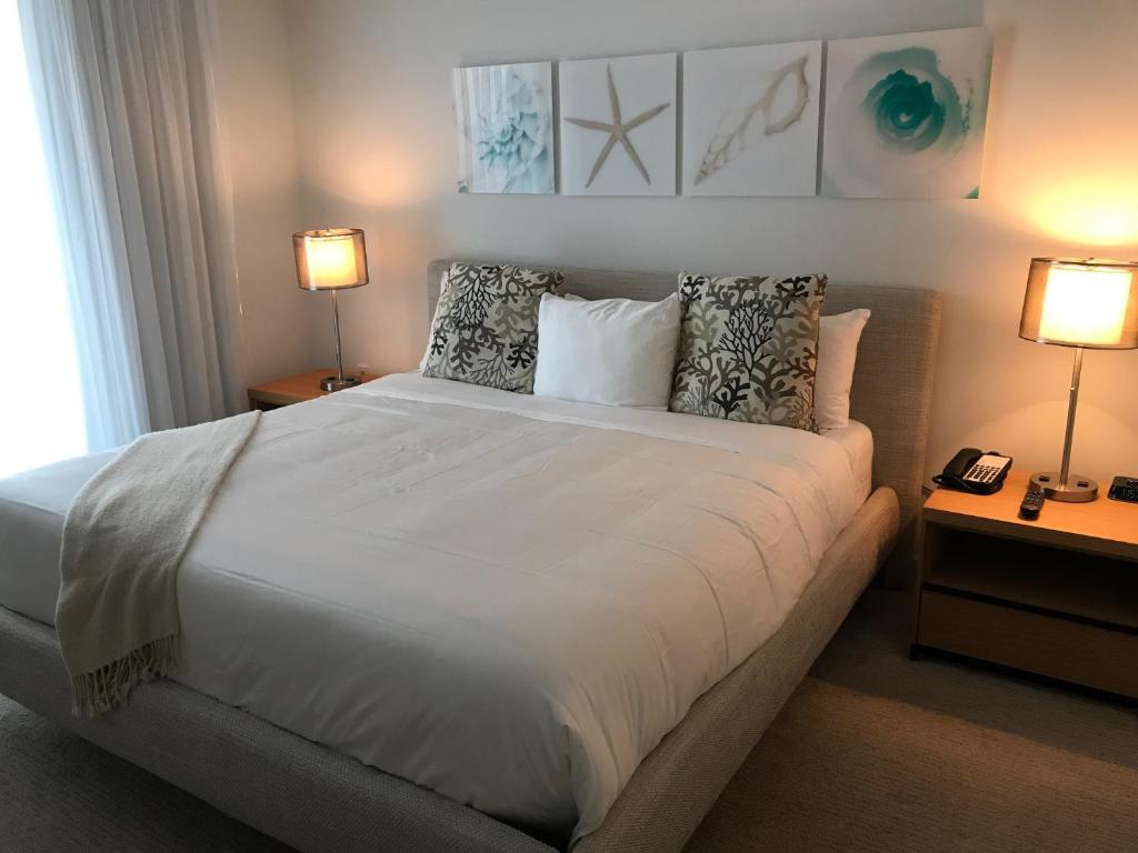 1 dormitorio con 1 cama blanca grande y 2 lámparas en Beach Walk Resort De Lux Apartment, en Hallandale Beach