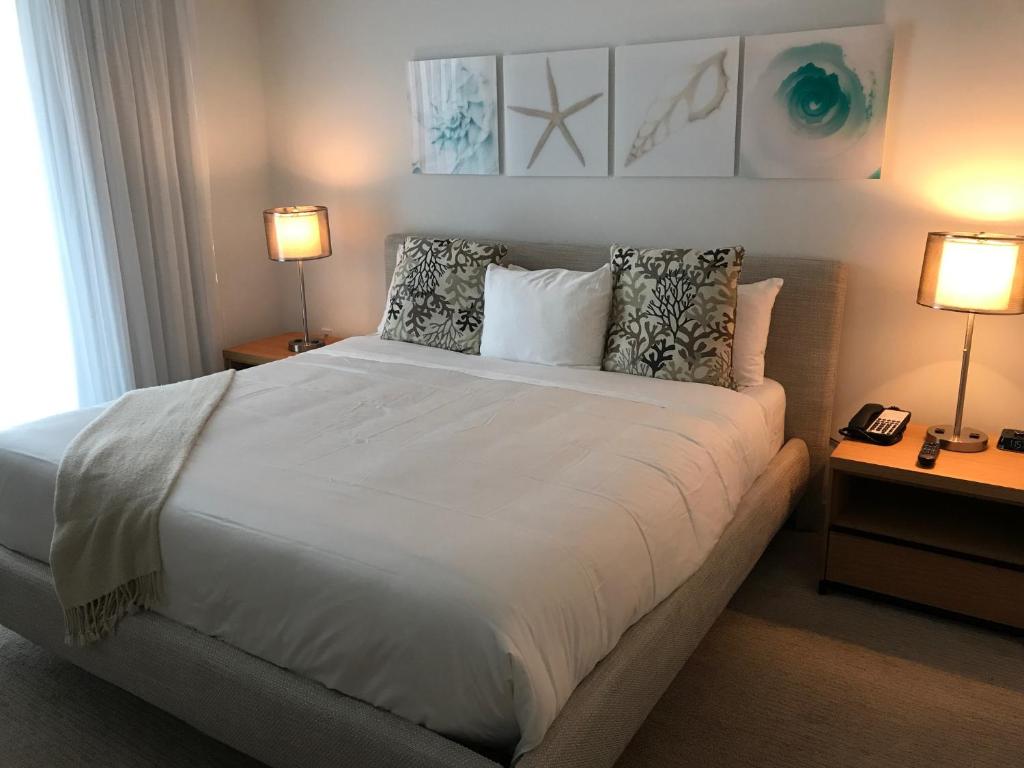 a bedroom with a large white bed with two lamps at Beach Walk Resort De Lux Apartment in Hallandale Beach