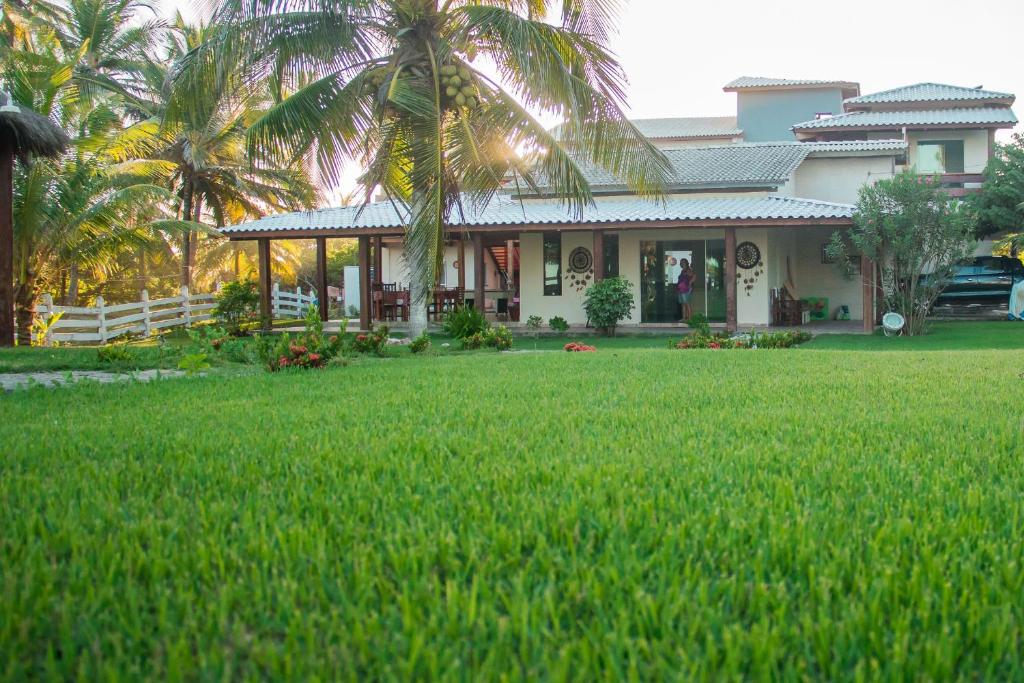 Una casa con un césped verde delante de ella. en João Praia Hotel, en Maraú