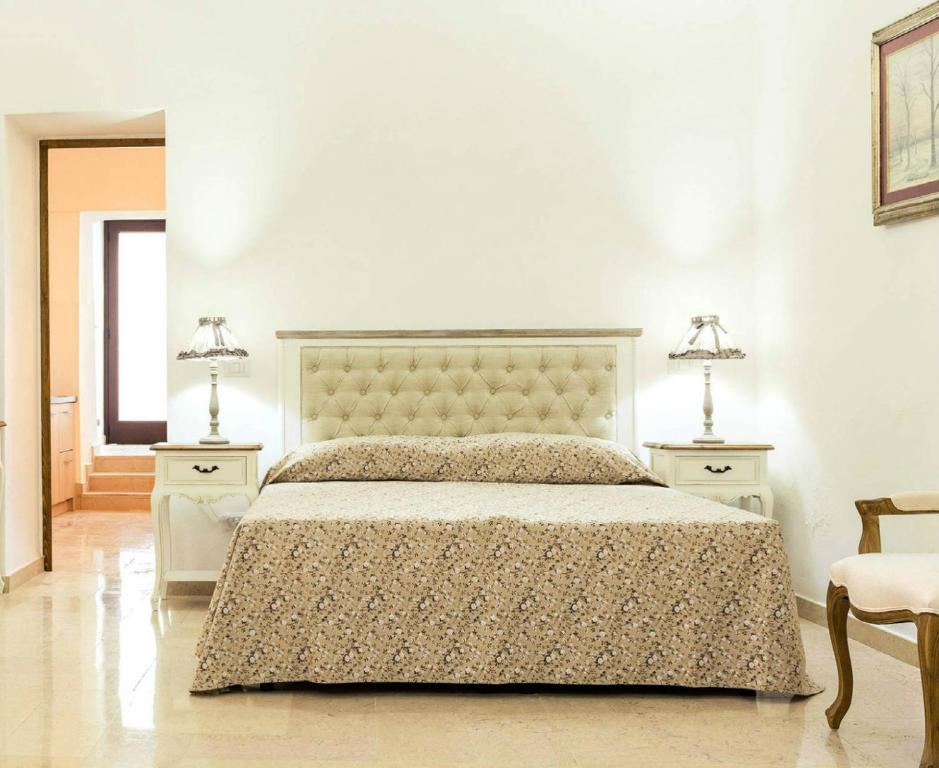 a bedroom with a large bed with two tables and two lamps at Palazzo Cavoti in Galatina