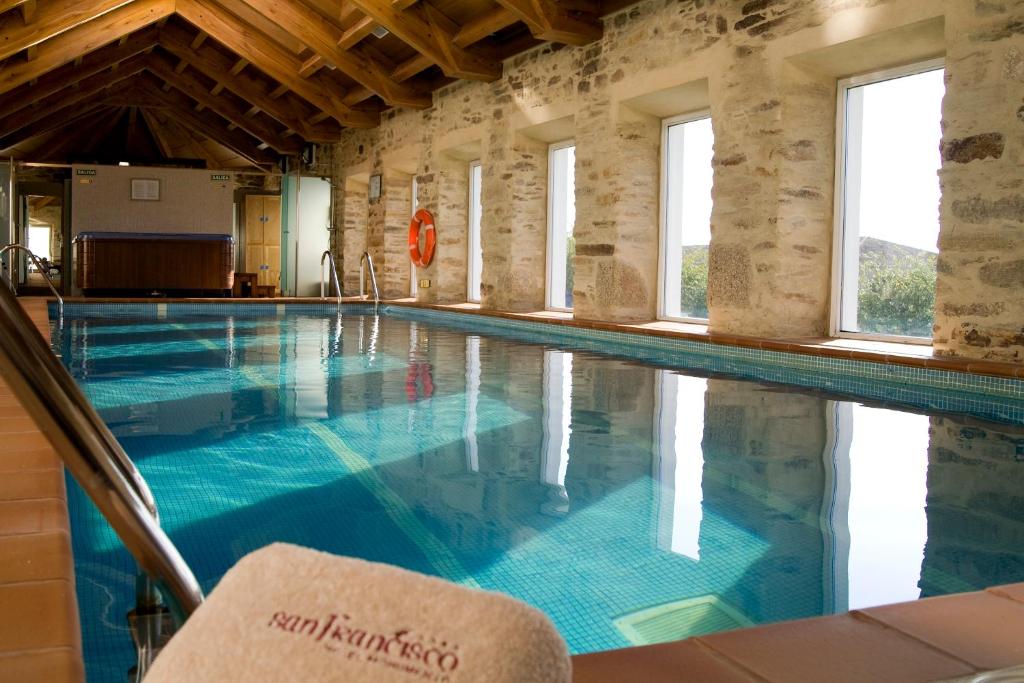 uma piscina com água azul num edifício com janelas em San Francisco Hotel Monumento em Santiago de Compostela