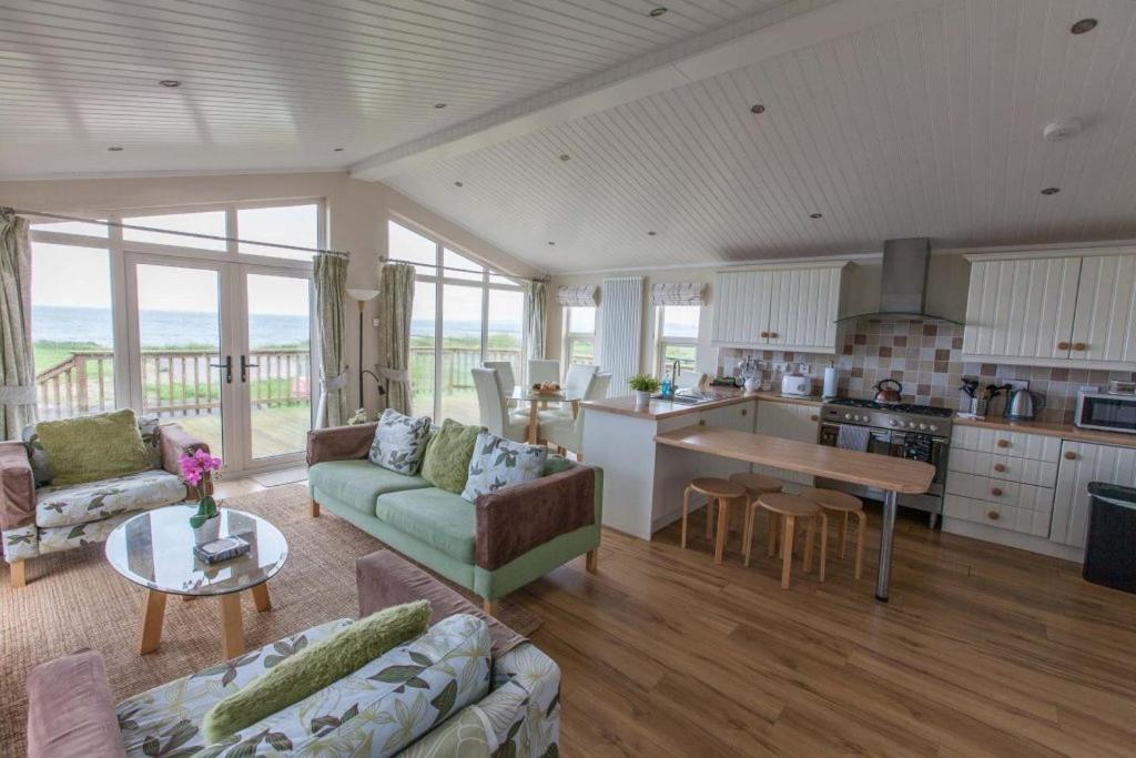 eine Küche und ein Wohnzimmer mit einem Sofa und einem Tisch in der Unterkunft Cloughey holiday lodge in Kirkistown