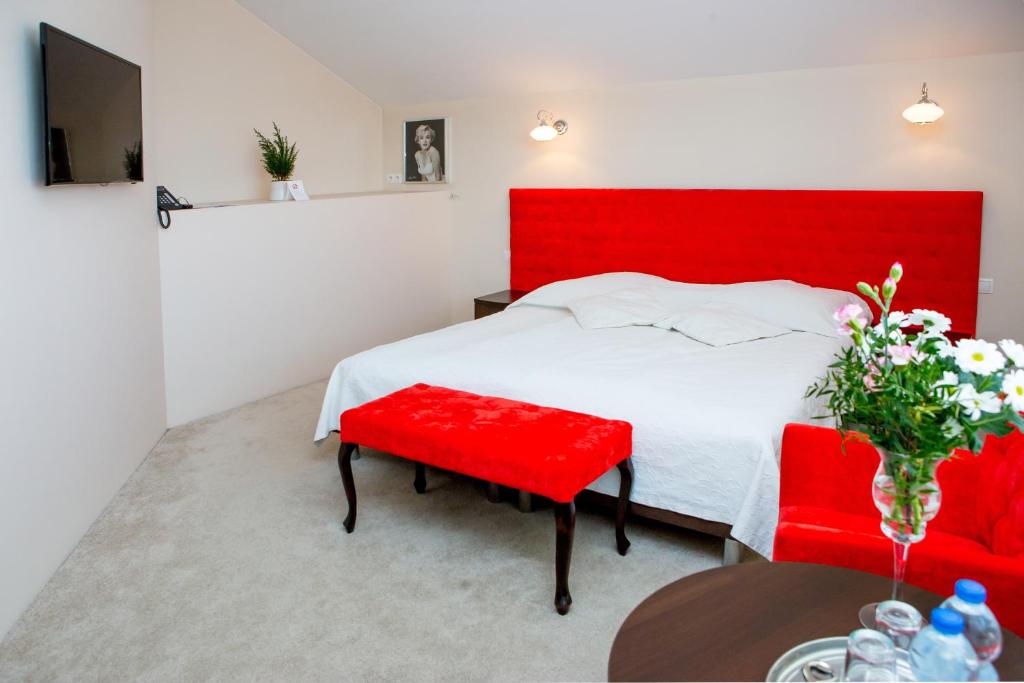 1 dormitorio con cama roja y banco rojo en Hotel Alexandra, en Pobiedziska