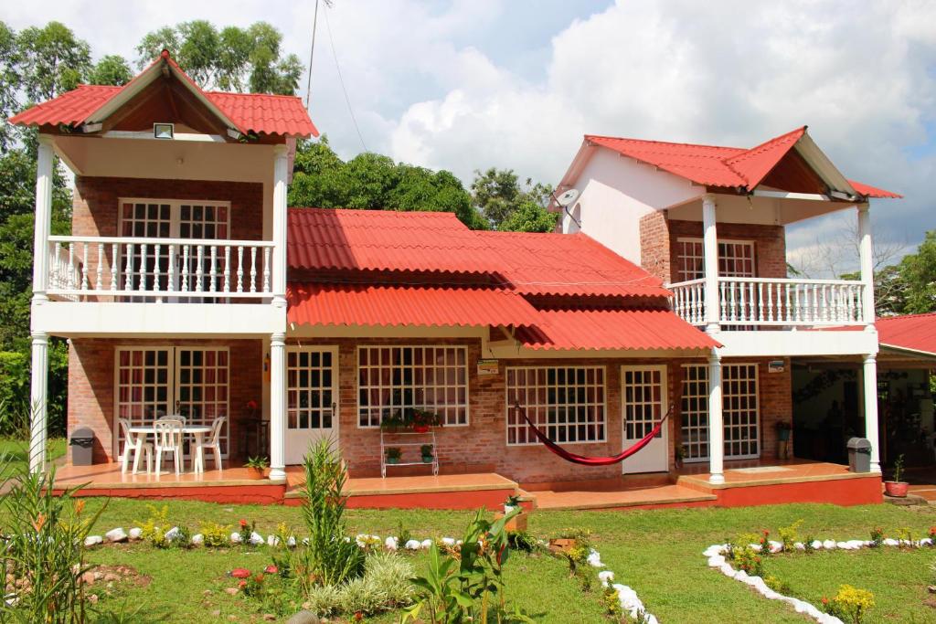 uma casa com um telhado vermelho e um quintal em Hotel finca Carmentea em Restrepo