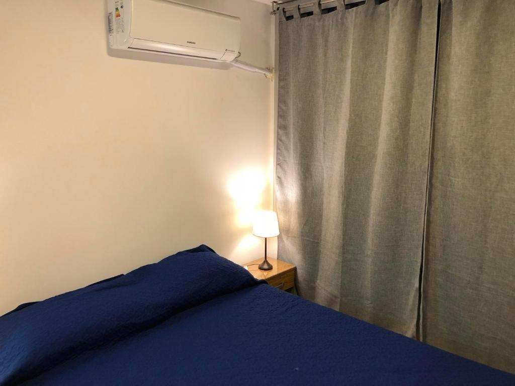 Un dormitorio con una cama azul y una ventana en Residencia Pasco en Rosario