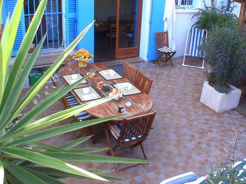 una mesa de madera y sillas en un patio en Les Chambres de Solliès, en Solliès-Pont