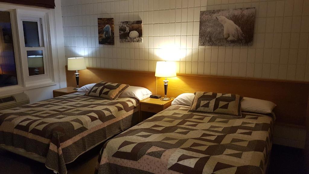 a hotel room with two beds and two lamps at Pinawa Motel in Pinawa